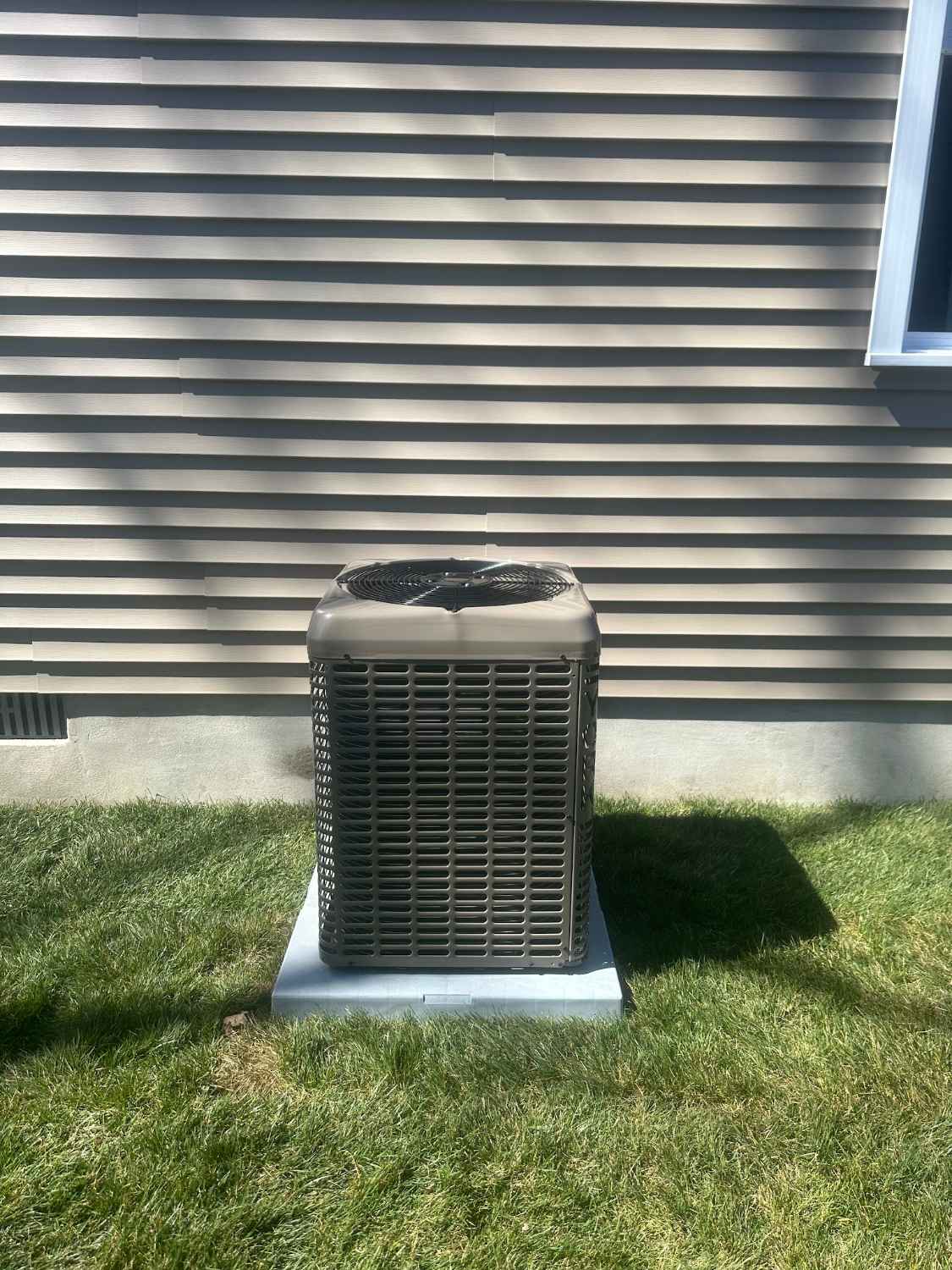 Air conditioning condenser on the lawn beside a sided home in Avalon NJ